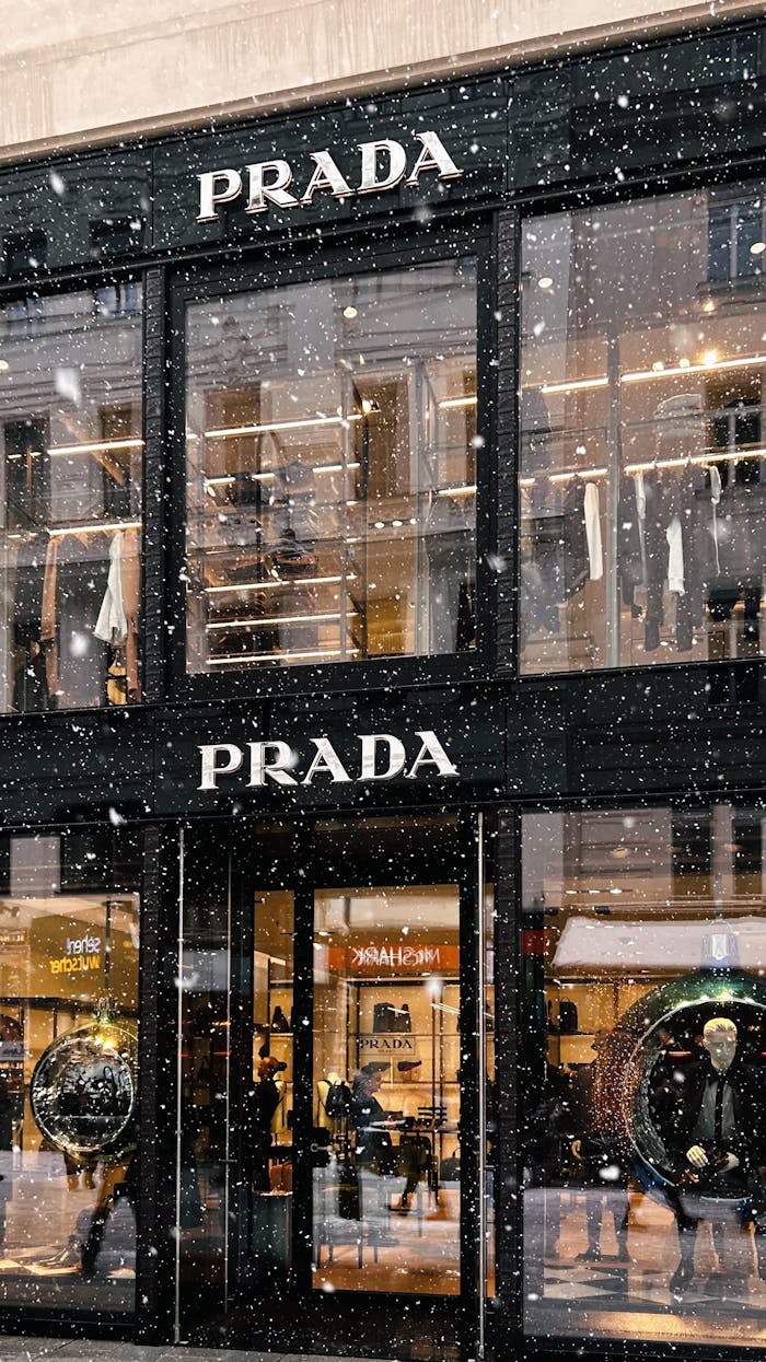 why-choose-us Captivating snowfall at Prada storefront, showcasing fashion during winter.